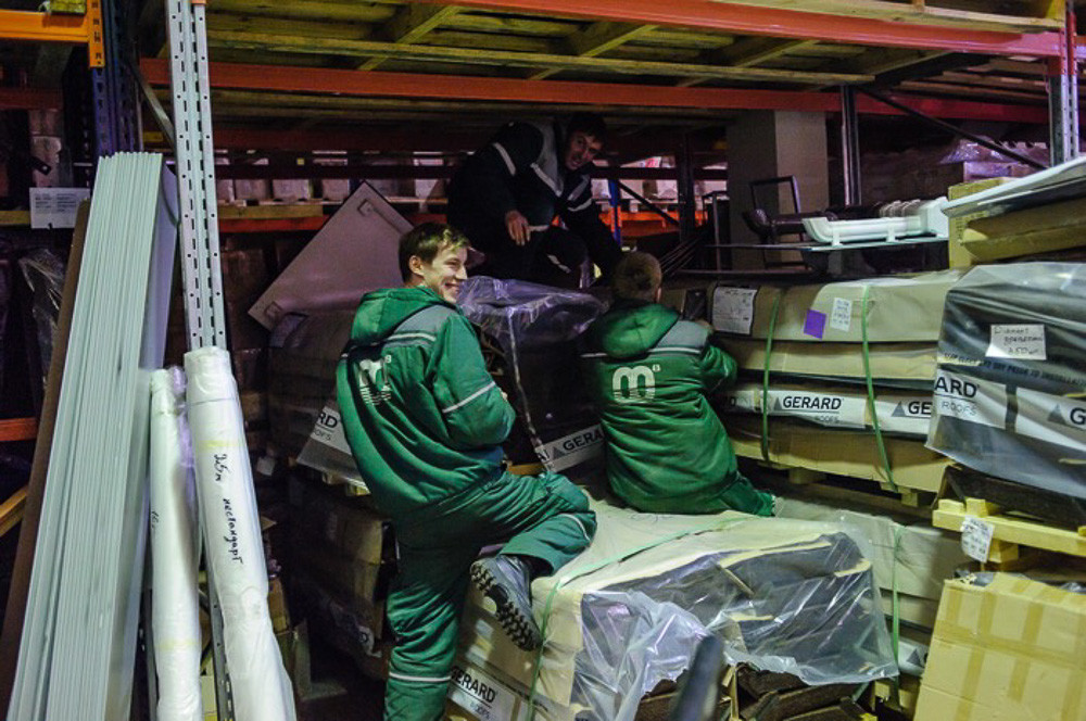 В течение дня рабочие склада загружают грузовые машины материалами для поставки в филиалы.
